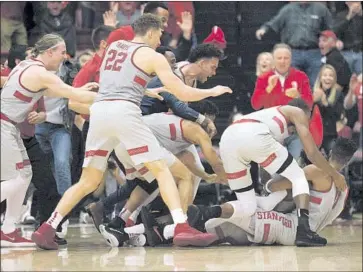  ?? D. Ross Cameron Associated Press ?? DAEJON DAVIS is mobbed by Stanford Cardinal teammates after making a basket from 50 feet at the buzzer to defeat USC, which took the lead on a basket by Jordan McLaughlin with 1.7 seconds to play.