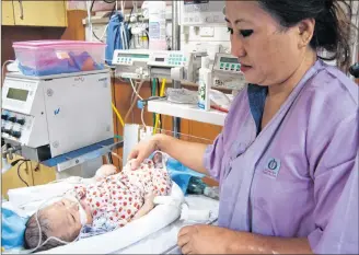  ?? CP PHOTO ?? Vikali A Zhimomi touches her grandson Atomika in Sir Ganga Ram Hospital in New Delhi on April, 9, 2018. She isn’t allowed to pick him up because his body is too fragile.