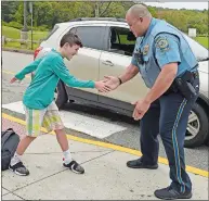  ?? SEAN D. ELLIOT/THE DAY ?? Waterford police Officer Dan Lane exchanges a secret handshake with student Trevor Stringer as Lane greets students at morning drop-off Thursday during his duty as school resource officer at Clark Lane Middle School. Lane spent the last 17 years as a K-9 officer with the town before moving over to the schools beat this year.