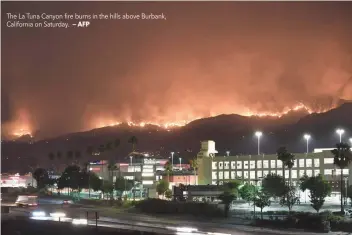  ?? — AFP ?? The La Tuna Canyon fire burns in the hills above Burbank, California on Saturday.