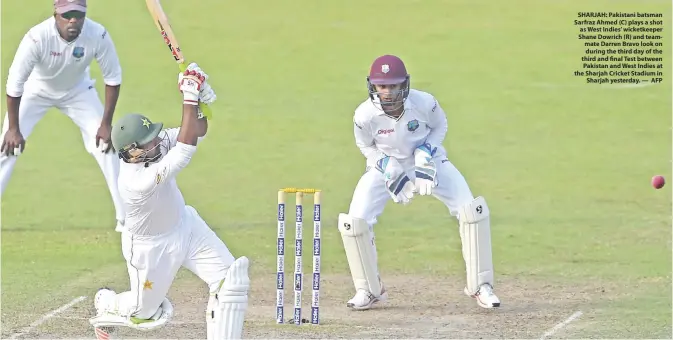  ??  ?? SHARJAH: Pakistani batsman Sarfraz Ahmed (C) plays a shot as West Indies’ wicketkeep­er Shane Dowrich (R) and teammate Darren Bravo look on during the third day of the third and final Test between Pakistan and West Indies at the Sharjah Cricket Stadium...