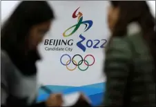  ?? AP FILE PHOTO/ANDY WONG ?? In this 2014 file photo, journalist­s chat near the Beijing’s bid for the 2022 Winter Olympics logo after attending a media briefing at the Beijing Olympics Headquarte­rs in Beijing, China.