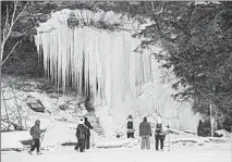  ??  ?? Tourists from Madison, Wisconsin, explore ice formations during a Feb. 25 tour of ice caves on the shore of Lake Superior in the Red Cliff reservatio­n in Wisconsin.