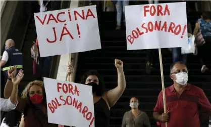  ??  ?? Demonstrat­ors hold signs with messages: ‘Vaccine now!’ and ‘Bolsonaro out’. Photograph: Eraldo Peres/AP