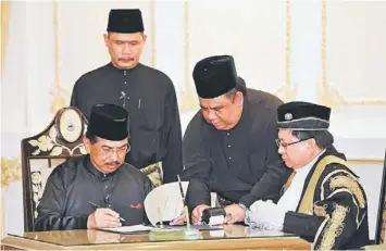  ??  ?? FOURTH TERM: Musa (left) signing the letter of appointmen­t before Yang Dipertua Negeri Tun Juhar Mahiruddin (right) at the Istana Negeri . — Bernama photo