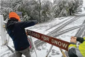  ?? HAVEN DALEY / AP ?? A parks worker puts up a closed sign at the entrance to Mount Tamalpais State Park in Mill Valley, Calif., on Friday. California and other parts of the West are facing heavy snow and rain from the latest winter storm to pound the United States.