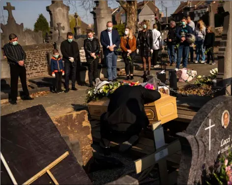  ?? AP FILE PHOTO/ ?? In this April 8 file photo, a relative of Margodt Genevieve, who died due to COVID-19, grieves over her coffin during her funeral ceremony at the Montignies cemetery in Charleroi, Belgium.