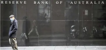  ??  ?? Hard times: A pedestrian wearing a face mask walks past the Reserve Bank of Australia building. The bank has painted a gloomy picture for the coming months, predicting the jobless rate would spike to 10% later this year. — Bloomberg