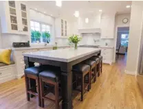  ??  ?? Clockwise, from top left: Homeowners Jennifer and Shane Palmer stand in front of a jade dragon carving from Taiwan. The white carpet in the living room was replaced with oak hardwood flooring. The teak settee is from Indonesia. In the kitchen, the...