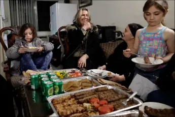  ?? AP PHOTO ?? Nadia Hanan Madalo (center) talks with her mother, Alyshooa Kannah (second from right) and other family members as she sits down for a meal in her brother’s apartment Thursday in El Cajon after arriving to the United States.