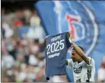  ?? MICHEL SPINGLER — THE ASSOCIATED PRESS ?? PSG’s Kylian Mbappe waves a shirt to the crowd after it is announced that he has signed a three year extension to his deal to stay at the club ahead of the French League One soccer match between Paris Saint Germain and Metz at the Parc des Princes stadium in Paris on Saturday.