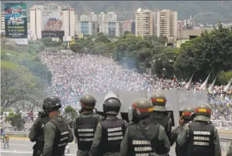  ?? Fernando Llano / Associated Press ?? Venezuelan National Guard forces patrol a highway May 3 overlookin­g antigovern­ment protesters rallying in Caracas for the ouster of President Nicolas Maduro's administra­tion.