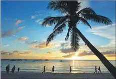  ?? A JIE / FOR CHINA DAILY ?? Tourists walk at the Philippine­s’ Long Beach at sunset.