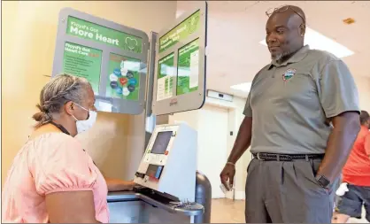  ?? Ryan Smith, Floyd Medical Center ?? Envision Center Director Greg Shropshire shows Shawana Sullivan how to use the blood pressure kiosk at the Northwest Georgia Housing Authority’s Frost and Barron high rise apartments.