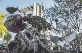  ?? Ulet Ifansasti, Getty Images AsiaPac ?? A damaged motorcycle is seen outside of Surabaya Centre Pentecosta­l Church, as they clean the road following a blast at the church a day earlier on May 14, 2018 in Surabaya, Indonesia.