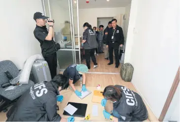  ?? PHOTO COURTESY OF THE DSI ?? Forensic specialist­s carefully handle documents and other pieces of evidence seized during a raid on an alleged cross-border investment fraud ring. The ring reportedly caused 1.7 billion baht in damage to Thai clients.