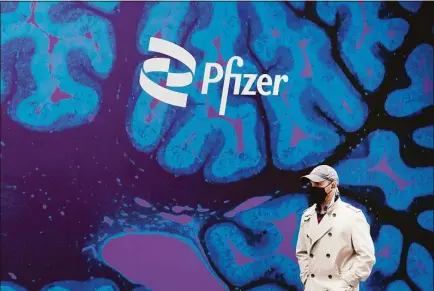  ?? Mark Lennihan / Associated Press file photo ?? A man walks by Pfizer headquarte­rs on Feb. 5, 2021 in New York. Pfizer is spending more than $11 billion to buy the remaining portion of migraine treatment maker Biohaven Pharmaceut­icals it does not already own.