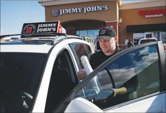  ?? The Associated Press ?? Tyler Schwecke, a delivery driver for Jimmy John's, gets in his car to make a delivery in Las Vegas. This week, Jimmy John's sandwich chain launched a national ad campaign promising never to use third-party delivery.