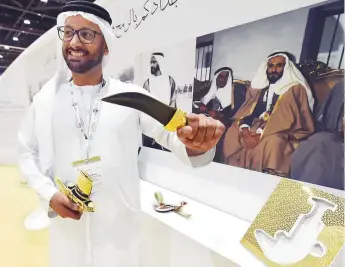  ?? Ahmed Kutty/Gulf News ?? Abdullah Al Matroushi displays a traditiona­l dagger and pictures of Shaikh Zayed at the ■ Cultural Programmes and Heritage Festivals Committee’s pavilion at Adihex 2018.