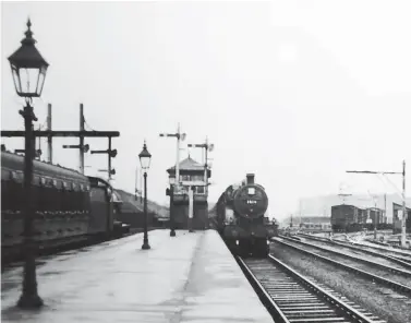  ??  ?? On 21 September 1938, Midland Railway-built Deeley Compound No 1018 runs into Hellifield station and past the South Junction signal box as a Fowler ‘2P’ class 4-4-0 waits in the south bay platform with a local passenger train for the former Lancashire & Yorkshire Railway route to Blackburn and Manchester; the ex-Midland and ex-L&YR goods yards were located either side of the line to Blackburn. The driver of No 1018 has shut off steam on the downhill gradient from Bell Busk to observe the speed restrictio­n over the junction and into the platforms. No 1018 was released from Derby Works in April 1906 as MR No 1013 and was superheate­d in December 1926. Its withdrawal would come about in July 1948 from Kentish Town shed.