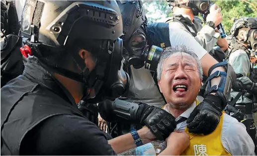  ?? AP ?? Richard Chan, a candidate for the district council elections, reacts after being pepper-sprayed by police in Hong Kong.