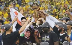  ?? AP ?? Golden State Warriors players, coaches and owners hold up the NBA Championsh­ip trophy following the series win last year.