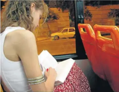  ?? RUESGA BONO ?? Una joven lee un libro en un autobús urbano.