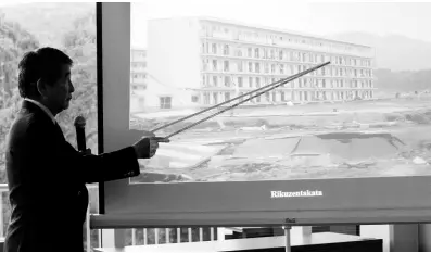  ?? IAN ALLEN PHOTOS ?? Yukio Okamoto, a former adviser to two of Japan’s prime ministers, points to the height at which floodwater­s reached following a tsunami in Japan in 2011. He was delivering a lecture at The University of the West Indies Regional Headquarte­rs in St Andrew on Friday.