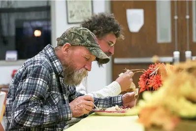  ?? Staff photo by Hunt Mercier ?? ■ Dwight Clark and James Scarl eat their Thanksgivi­ng dinners at The Salvation Army’s Center of Hope on Thursday in Texarkana, Ark. The Salvation Army gathered enough food to feed the residents and the homeless of Texarkana.