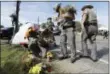  ?? ERIC GAY — THE ASSOCIATED PRESS ?? Law enforcemen­t officials move flowers left at the scene of a shooting at the First Baptist Church of Sutherland Springs, Monday in Sutherland Springs, Texas. A man opened fire inside the church in the small South Texas community on Sunday, killing and...