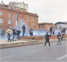  ??  ?? ► Manifestan­tes huyen del gas lacrimógen­o en enfrentami­entos, ayer en Toulouse.