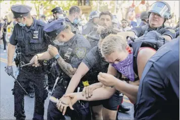  ?? Seth Wenig / Associated Press ?? New York Police officers use pepper spray on protesters during a demonstrat­ion Saturday in Brooklyn. Protests were held throughout the city over the death of George Floyd.
