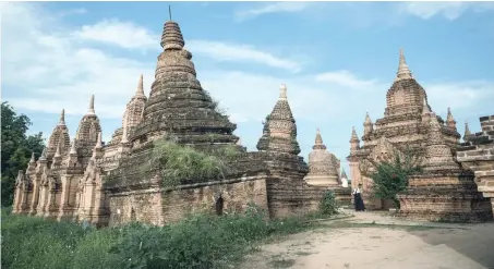  ?? — AFP ?? A tour guide walks between monuments at Khaymingha temple in Bagan. Located in central Myanmar, Bagan is home to more than 2,000 ancient Buddhist monuments deeply revered in the Buddhistma­jority nation and is one of the country’s most popular tourist...