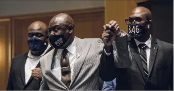  ?? Stephen Maturen / Getty Images ?? Attorney Ben Crump, center, holds up the hand of Philonise Floyd, right, and is joined by Rodney Floyd, left, as they enter a press conference Friday in Minneapoli­s, Minn. The city has agreed to pay a record $27 million settlement to the family of George Floyd after his death in the custody of Minneapoli­s Police.