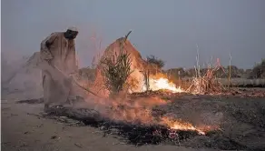  ??  ?? People running from Boko Haram have settled along Niger’s National Route 1, like this man burning grass by his hut. Top, empty containers at a water point along the road.