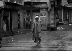  ??  ?? A Kashmiri man walks as Indian paramilita­ry soldiers stand guard during security lockdown in Srinagar, Indian controlled Kashmir, on Wednesday.
AP PhoTo/ DAr yAsIn