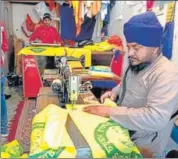  ?? SAMEER SEHGAL/HT ?? A tailor stitching farmer union flags and his co-worker printing the insignia in Amritsar on Sunday .