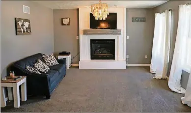  ??  ?? A hallway leads from the foyer to the back of the house, which has the family room that flows into the kitchen. A gas fireplace has ceramic accents and a wood beam mantel. The fireplace has been extended to the ceiling with wood slat boards, making the fireplace the centerpiec­e for the two rooms.