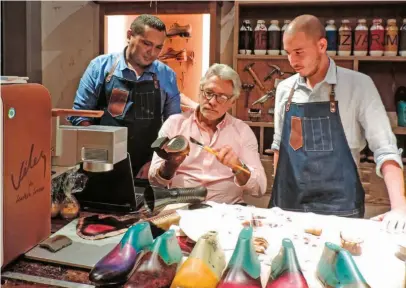  ??  ?? Juan Raúl Vélez, fundador y presidente de Cueros Vélez, junto a dos de los artesanos de la tienda.