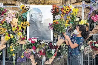  ?? THE ASSOCIATED PRESS ?? Flowers are placed around a portrait of Anglican Archbishop Desmond Tutu at St. George’s Catherdral in Cape Town, South Africa, Monday. South Africa is holding a week of mourning for Tutu.