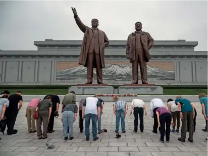  ?? AFP ?? A group of tourists bow before statues of North Korean leaders Kim Il-sung (left) and Kim Jong-il, on Mansu hill in Pyongyang. —