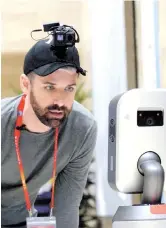 ??  ?? Andy Boreham interacts with a cute little robot in the media center. — Zhou Shengjie