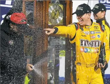  ?? Stacy Revere/Getty Images ?? Kyle Busch celebrates in Victory Lane after winning Sunday at Martinsvil­le Speedway, moving Joe Gibbs teammate Denny Hamlin out of his way in overtime.