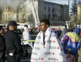  ?? BEN MARGOT — THE ASSOCIATED PRESS ?? An evacuee waits as firefighte­rs battle an early morning four alarm apartment fire Monday in Oakland.