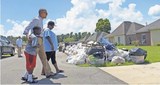  ?? SUSAN WALSH, AP ?? President Obama walks with a family to tour their flood- damaged home in the Castle Place neighborho­od of Baton Rouge. Obama made his first visit to flood- ravaged southern Louisiana.