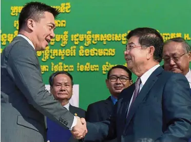  ??  ?? Deal sealed: Tang (left) shaking hands with Cambodia’s Minister of Mines and Energy Suy Sem at the signing ceremony. — AFP