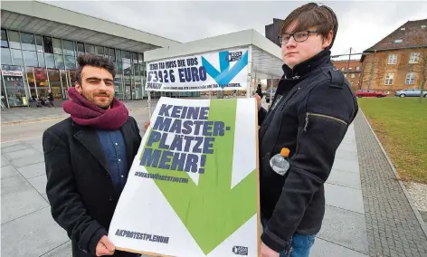  ?? FOTO: IRIS MAURER ?? Mit einer Plakat-Aktion wollen Soheil Hemmati-Ortakand (links) und Janosch Rudack vom Arbeitskre­is Krawall auf Missstände an der Saar-Universitä­t aufmerksam machen, die durch die vom Land auferlegte Sparlast entstanden sind.