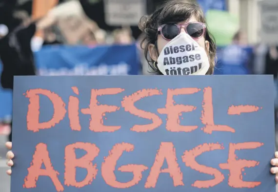  ??  ?? A protester wears a mask and holds a sign reading “Diesel-Abgase toeten!” (Diesel emission kills), in front of the Ministry of Transport, in Berlin.