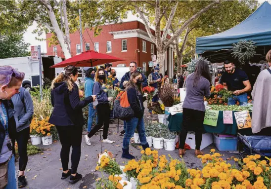  ?? Andri Tambunan / Special to The Chronicle ?? Shoppers buy flowers at the Midtown Farmers’ Market in Sacramento.