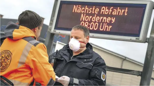  ?? Dpa-BILD: Schuldt ?? Ein Mitarbeite­r des Ordnungsam­ts kontrollie­rt in Norddeich vor der Fähre nach Norderney die Ausweise.
